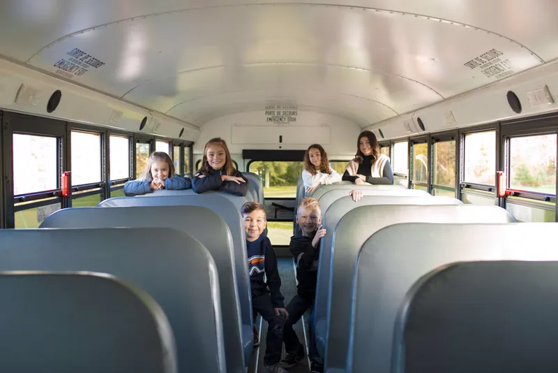 Six enfants souriants à bord d'un autobus scolaire Interbus