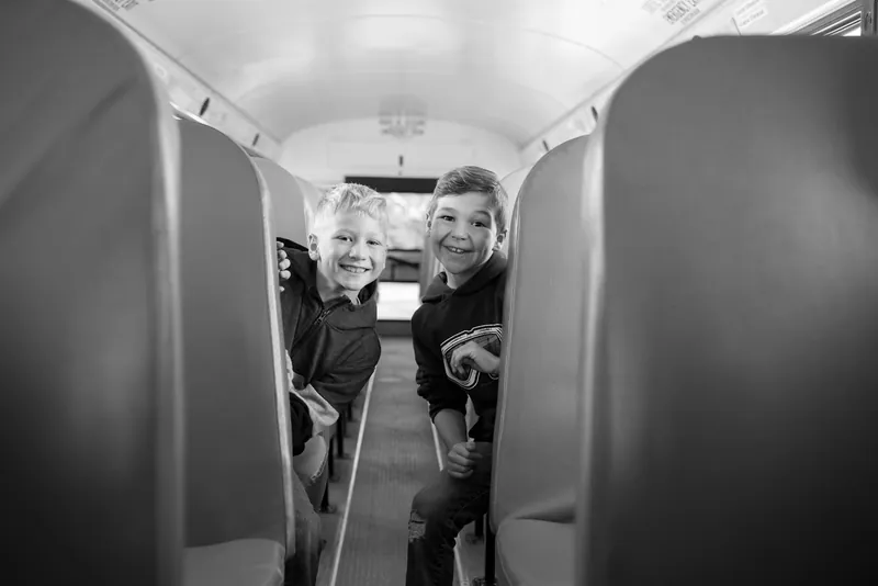 Deux garçons souriants entre les bancs d'un autobus scolaire